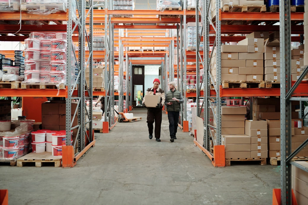 a front view of 2 person working inside a warehouse in logistics
